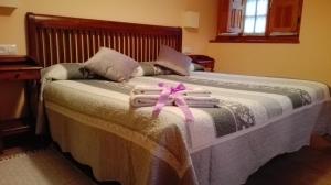 a bed with towels and a pink ribbon on it at Apartamentos Rurales Casa Marcelo in Veigas