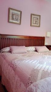 uma cama num quarto com duas fotografias na parede em Apartamentos Rurales Casa Marcelo em Veigas