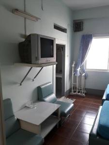 uma sala de estar com cadeiras, uma mesa e uma televisão em Anodard Hotel em Nakhon Sawan