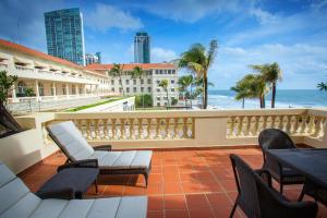 einen Balkon mit Stühlen, Tischen und Meerblick in der Unterkunft Galle Face Hotel in Colombo