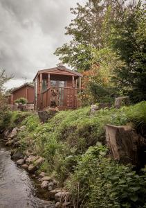 una pequeña casa en una colina junto a un río en Bear Lodge en Auchterarder