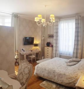ein Schlafzimmer mit einem Bett, einem Schreibtisch und einem Kronleuchter in der Unterkunft La Porte De Bretagne in Péronne