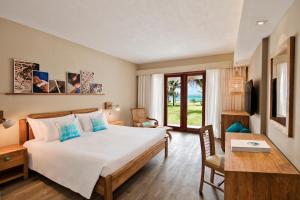 a hotel room with a bed and a desk and a room at C Mauritius in Belle Mare