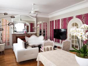 a living room with white furniture and pink wallpaper at La Porte De Bretagne in Péronne