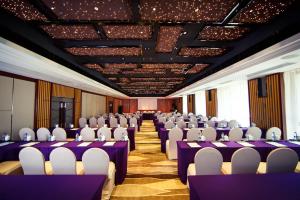 una sala de conferencias con mesas púrpuras y sillas blancas en Holiday Wuyang Hotel, en Hangzhou