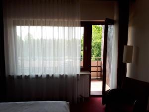 a bedroom with a bed and a window with a door at Hotel Restaurant Ramster in Schneverdingen