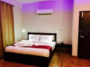 1 dormitorio con 1 cama grande y pared morada en The Park Residency en Greater Noida