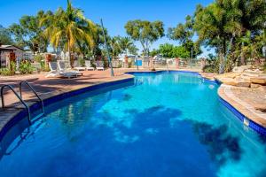 a swimming pool with blue water and palm trees at Discovery Parks - Port Hedland in Port Hedland