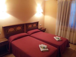 a bedroom with a red bed with two towels on it at Hospedería Prepirineo in Undués-Pintano +37 photos