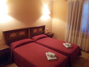 a bedroom with a red bed with two towels on it at Hospedería Prepirineo in Undués-Pintano