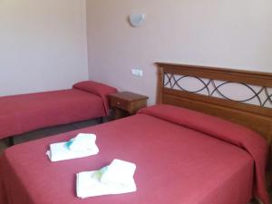 two beds in a room with red sheets and towels at Hospedería Prepirineo in Undués-Pintano