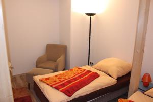 um quarto com uma cama, um candeeiro e uma cadeira em Pension Holly em Oschatz