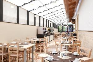 a restaurant with wooden tables and chairs and windows at Smooth Hotel Rome West in Rome