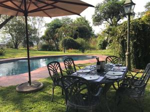 a table with chairs and an umbrella next to a pool at Cuckoos Nest Guest House in Louis Trichardt