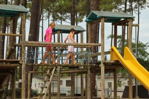 two children playing on a wooden playground at Camping Officiel Siblu Les Dunes de Contis in Saint-Julien-en-Born