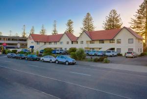 un grand bâtiment avec des voitures garées dans un parking dans l'établissement Bella Vista Motel Napier, à Napier