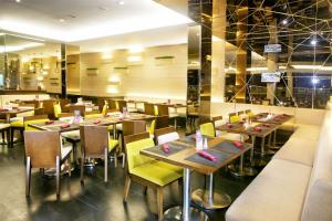 un restaurante con mesas de madera y sillas amarillas en Hotel Grand Zuri Muara Enim, en Muaraenim