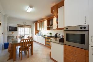 a kitchen with wooden cabinets and a table and chairs at Ericeira Sunset Lifestyle I in Ericeira