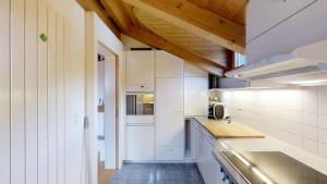 シルヴァプラーナにあるGkbの白いキャビネットと木製の天井が備わるキッチン