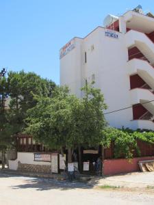 a white building with a tree in front of it at Emin Apart Hotel in Didim