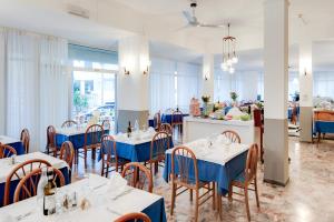 a restaurant with blue tables and chairs and a counter at Hotel Helvetia in Grado
