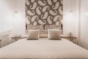 una camera da letto con un grande letto bianco con due cuscini di El Horno de los Bizcochos a Toledo