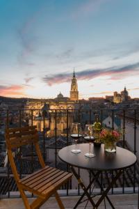 una mesa y una silla en un balcón con copas de vino en El Horno de los Bizcochos, en Toledo
