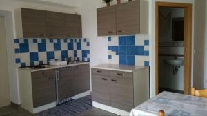 a kitchen with brown cabinets and blue and white tiles at Ferienwohnung "Bäderdreieck" in Haarbach