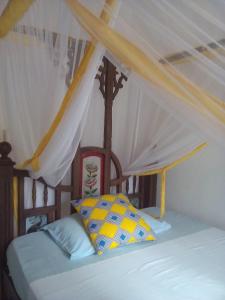 a bed with a white canopy and a yellow pillow at Kiponda B&B in Zanzibar City