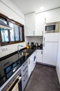 a kitchen with white cabinets and a sink at Apartamento Vista Oceano in Caniço