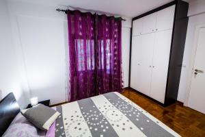 a bedroom with a bed with a purple curtain at Apartamento Vista Oceano in Caniço