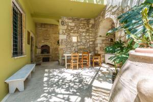eine Terrasse mit Tisch und Stühlen und einer Steinmauer in der Unterkunft Patrico in Káto Póros