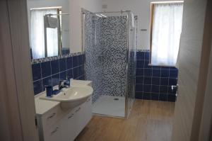 a bathroom with a sink and a shower with blue tiles at Holiday House Margherita in Brenzone sul Garda