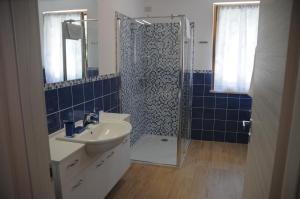 ein Badezimmer mit einem Waschbecken und einer Dusche mit blauen Fliesen in der Unterkunft Holiday House Margherita in Brenzone sul Garda