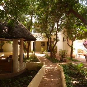 a courtyard with trees and a building with a sidewalk at La Venise Malienne in Bamako