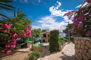 a house with a garden with pink flowers at Captain's Apartment in Rab