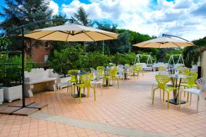 eine Terrasse mit Tischen, Stühlen und Sonnenschirmen in der Unterkunft Smooth Hotel Rome West in Rom