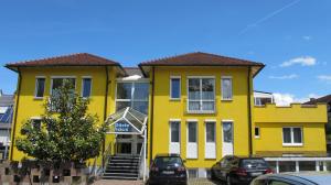 un bâtiment jaune avec des voitures garées devant lui dans l'établissement Gästehaus Wagner, à Bad Krozingen