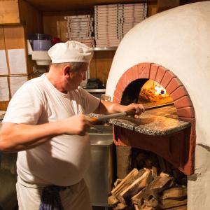 a man standing in front of a pizza oven at La Tambra - Residence - Central with Restaurant in Santa Cristina Gherdëina