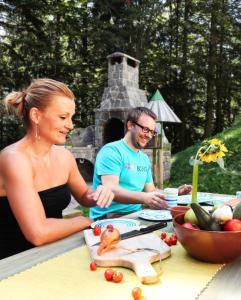 Ein Mann und eine Frau bereiten Essen an einem Tisch vor. in der Unterkunft Green Village Ruševec in Hočko Pohorje