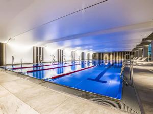 a large indoor swimming pool with blue water at VacationClub - Trzy Korony Piastów Apartment 2 in Świnoujście