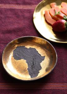 a gold plate with a map on it next to a plate of fruit at InAweStays Holiday Homes in Cape Town