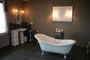 a bathroom with a bath tub and a sink at B&B La ferme du doux in Libramont