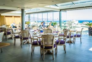 restauracja ze stołami i krzesłami oraz widokiem na ocean w obiekcie Castello City Hotel w Heraklionie