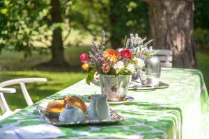 una mesa con un mantel con un jarrón de flores en Le Peonie, en Peveragno