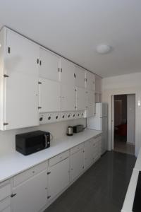 a white kitchen with white cabinets and a microwave at Suites Apartments in Cascais