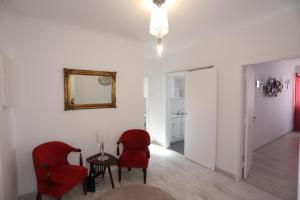 a living room with two red chairs and a table at Suites Apartments in Cascais