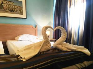 two towel swans sitting on top of a bed at Пансион Роди in Silistra