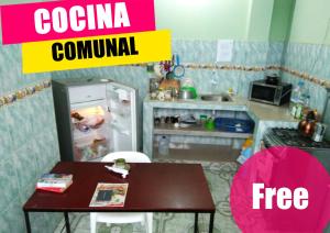 a small kitchen with a table and a refrigerator at Hostal Alcazaba in Puerto López