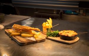 two cutting boards with food and french fries on a counter at Three Horseshoes Country Inn in Leek